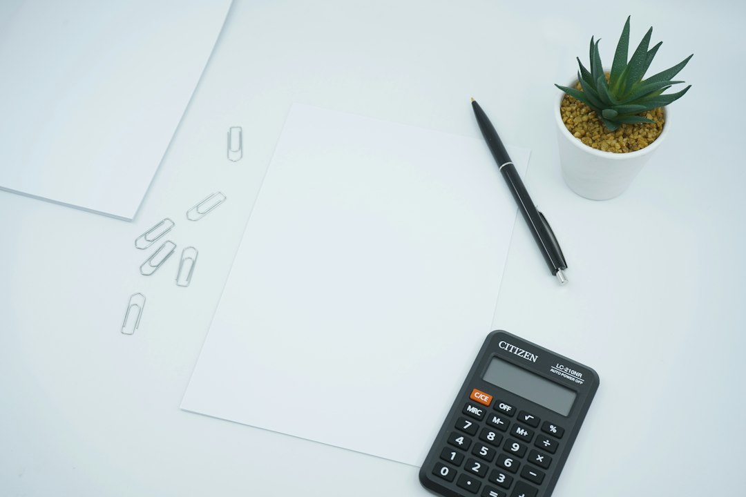 Calculator, pen and blank paper on a desk