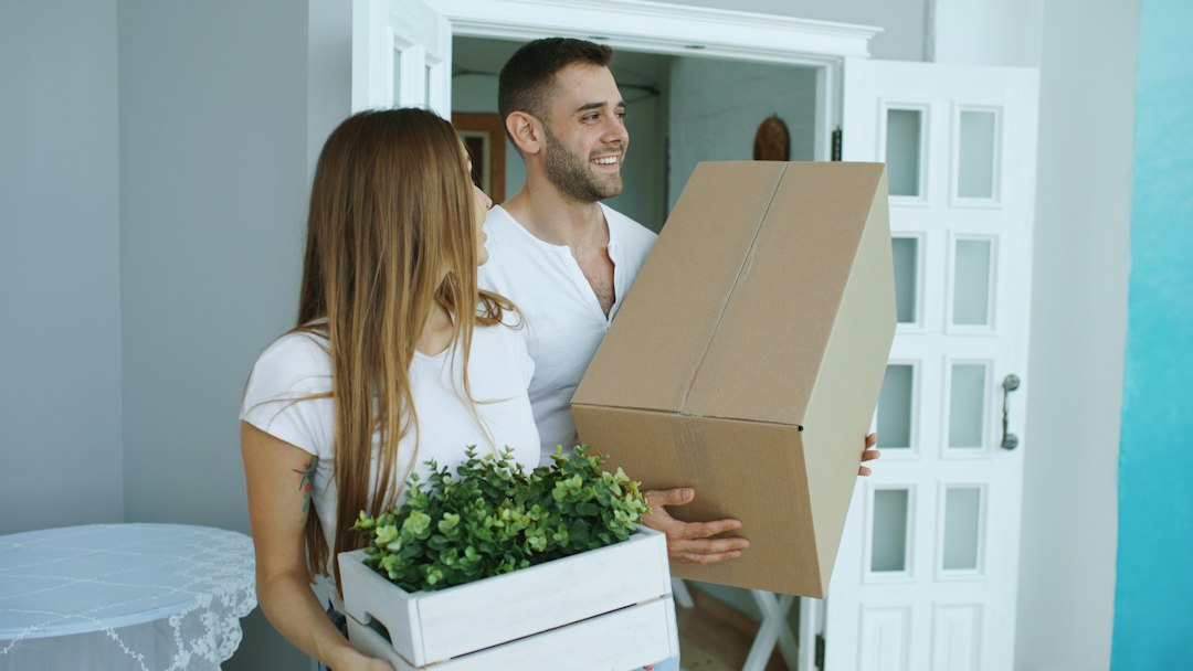 Two people holding a moving box inside a home