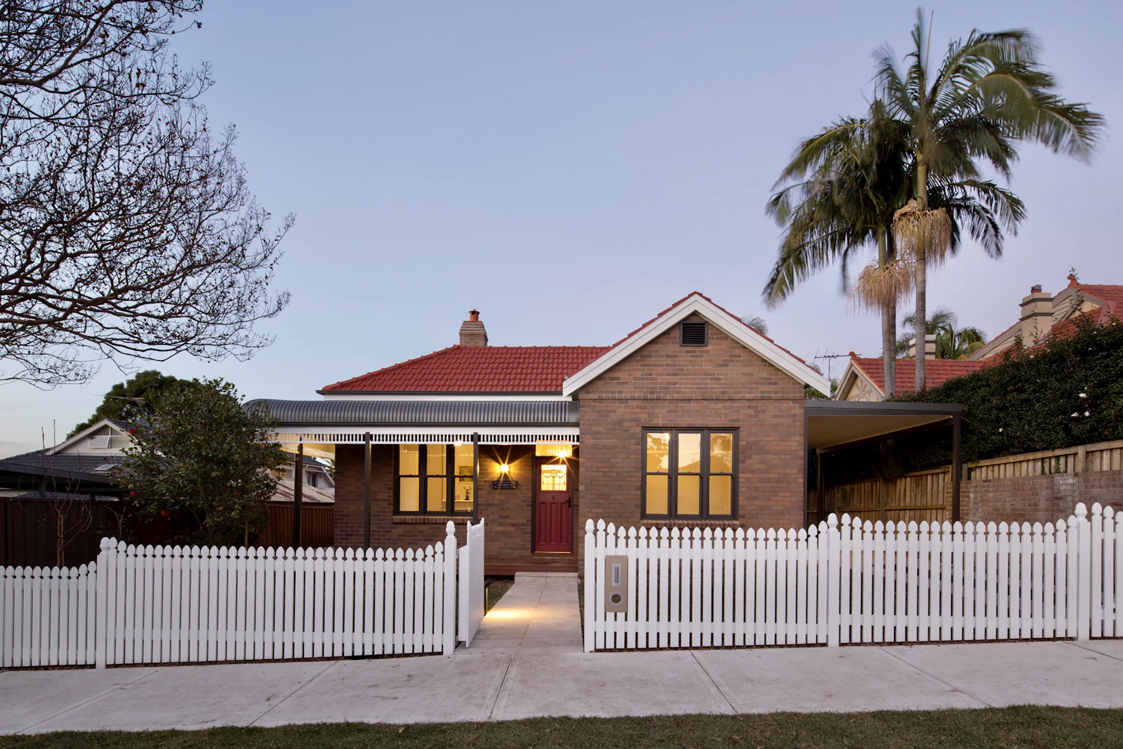 Brick house with a front fence at dusk