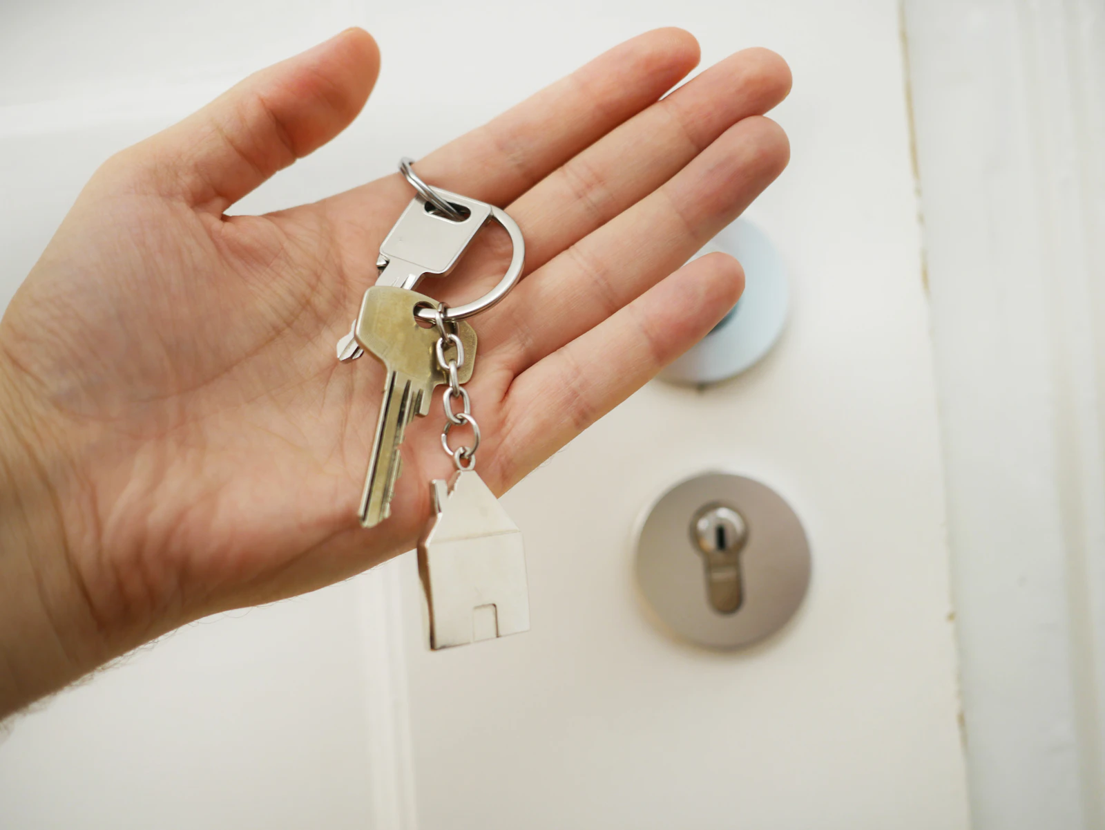Hand holding a key in front of a door lock