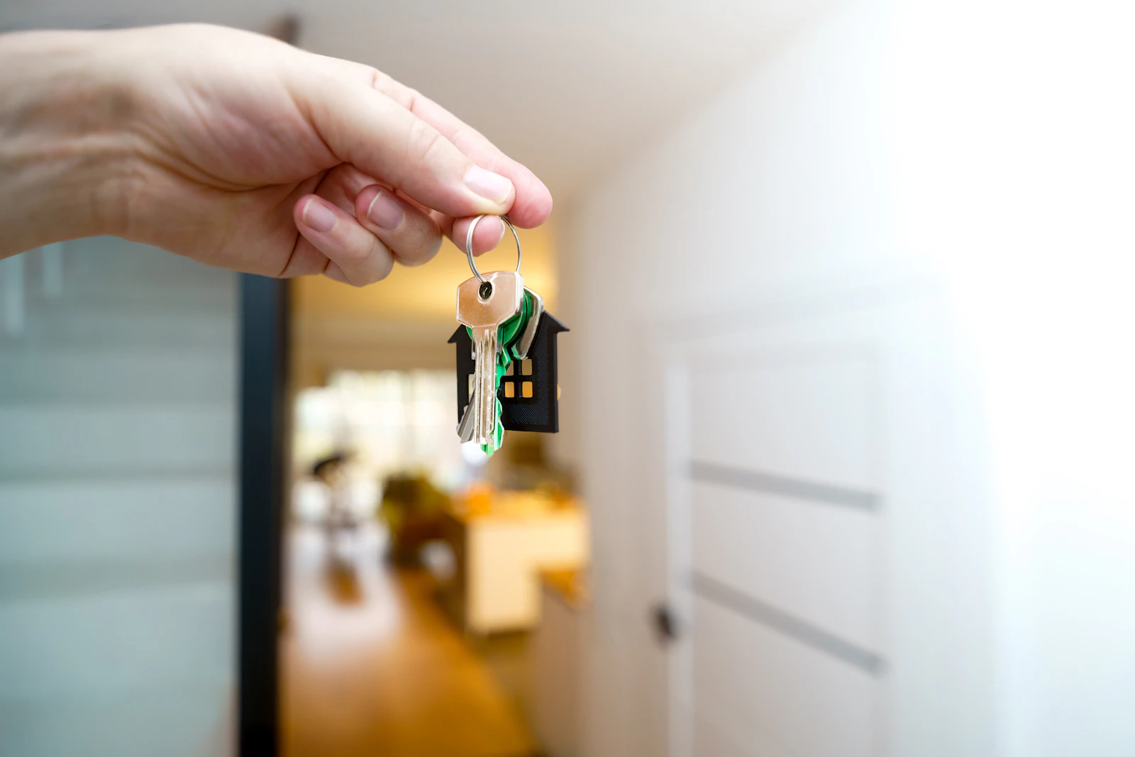 Hand holding keys beside an open front door