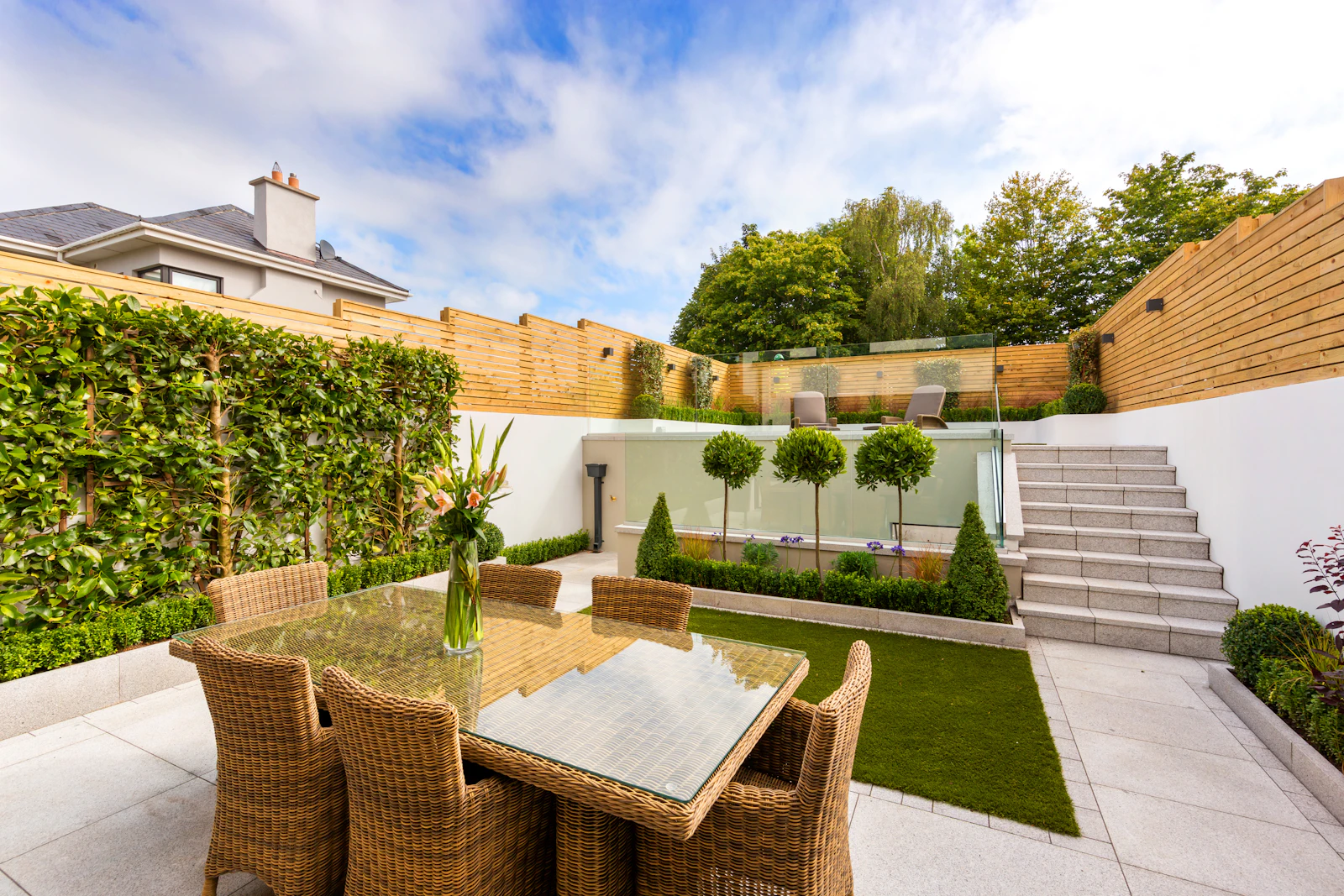 Paved courtyard with dining furniture and planted borders