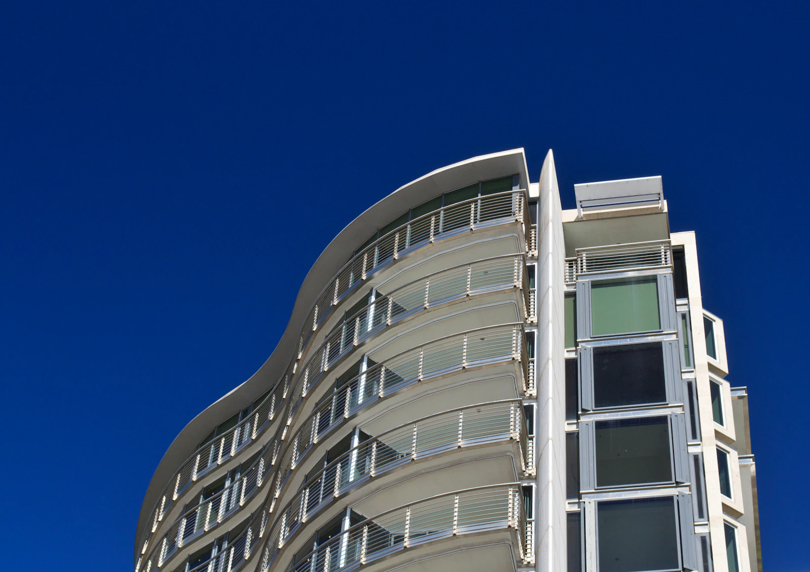 Curved apartment building viewed against a blue sky